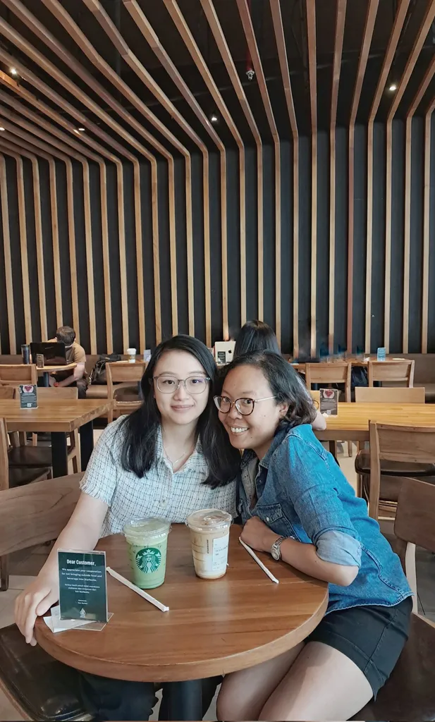 Ayu and Victoria sit in a cafe and look at the camera